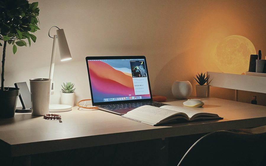 A desk lit by a lamp in the evening
